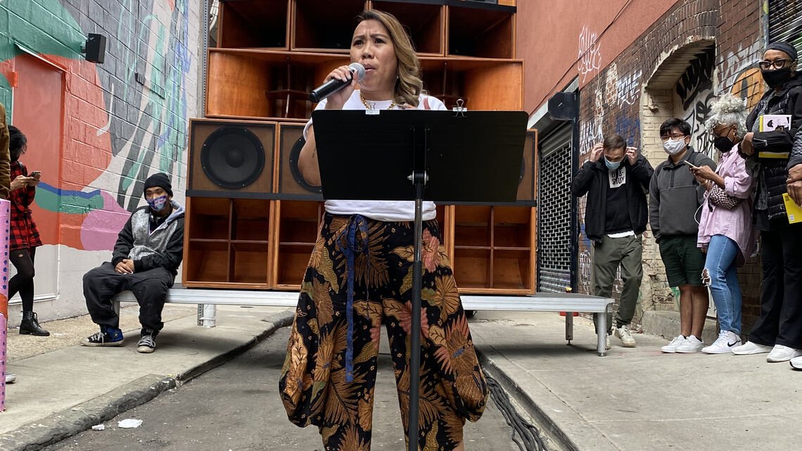Person speaking on a mic in an alleyway