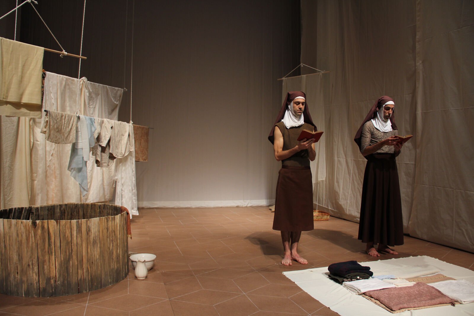 two men in nun outfits perform in front of hanging fabric